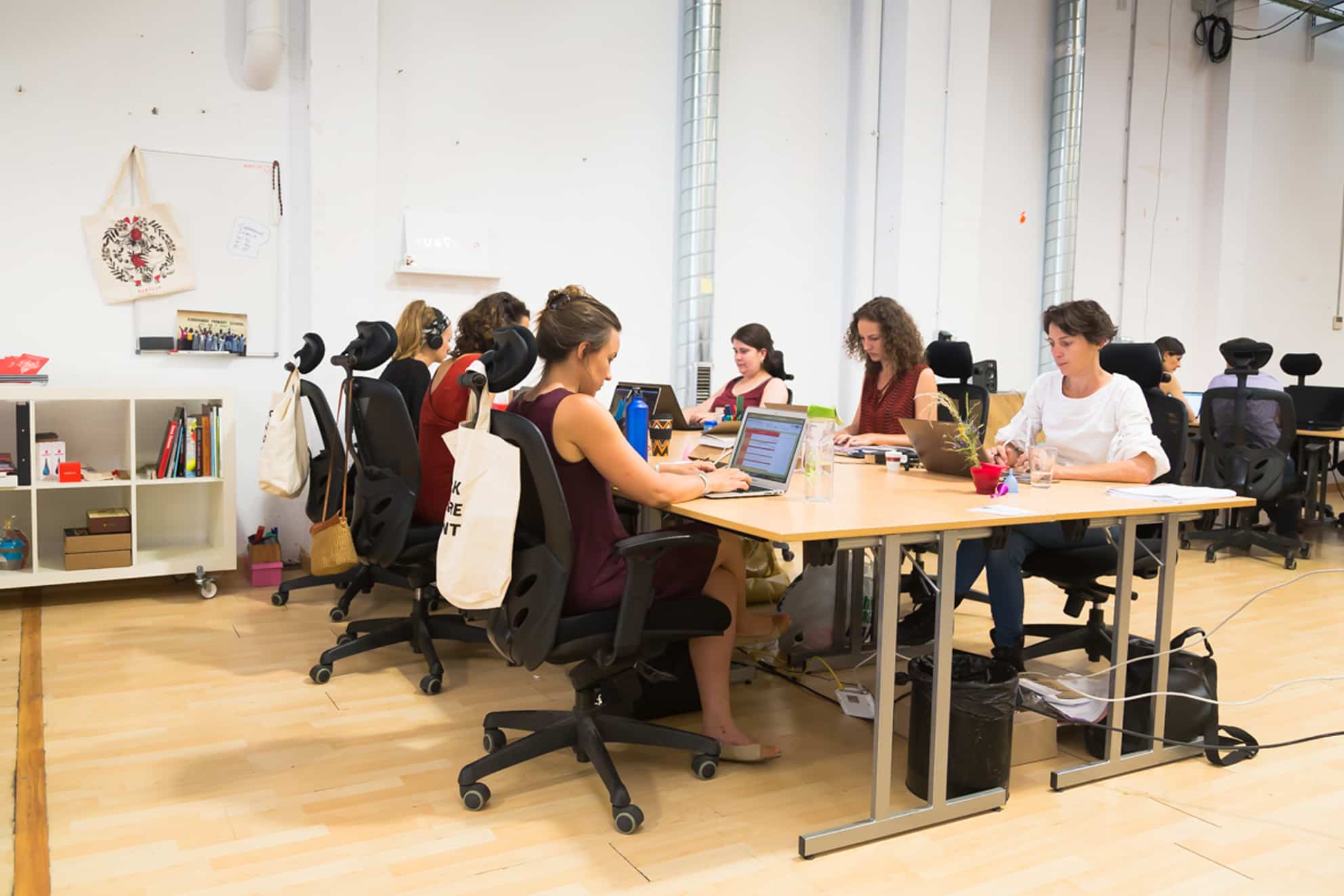 Equipo de trabajo en una isla de 4 mesas en el espacio abierto de coworking en Barcelona
