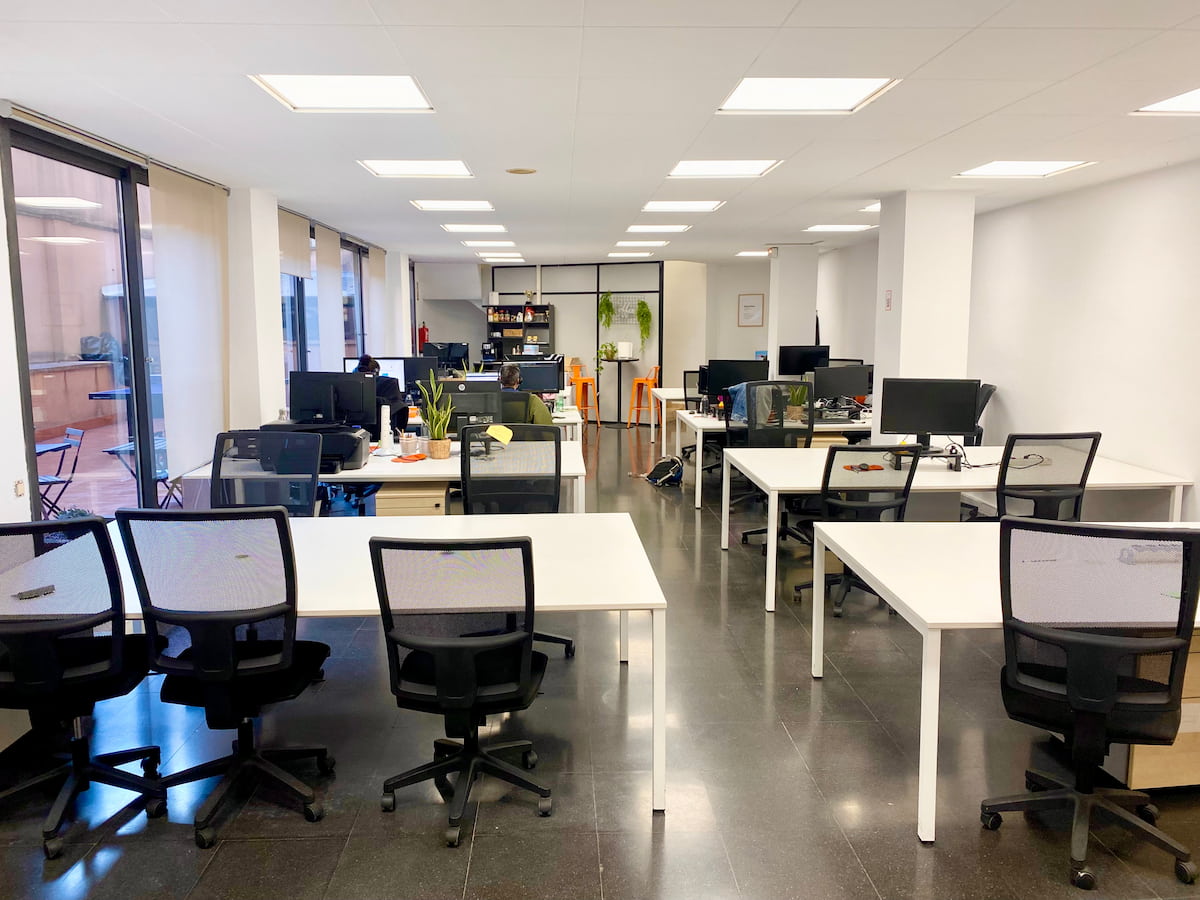 Mesas blancas con sillas negras en la oficina de CREC Mallorca